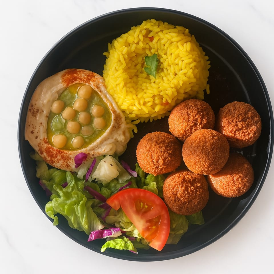 Middle-eastern platter with falafel, yellow rice, hummus with chickpeas, and a side salad.